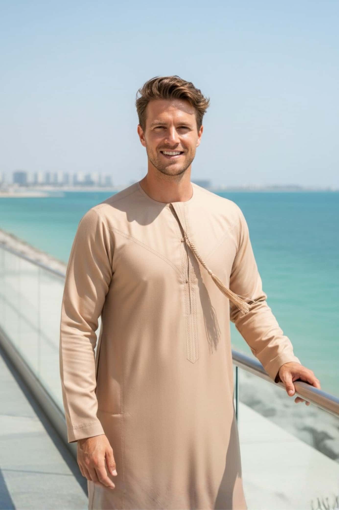 Western man wearing a sand stone colored kandora in the Abu Dhabi dunes, perfectly matching the desert landscape. 3